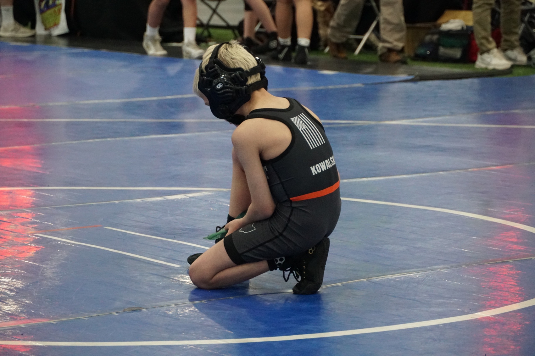 Wrestler kneeling on the blue mat before competition